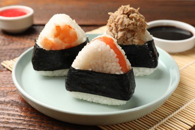 Photo of Tasty onigiri (Japanese rice balls) served on wooden table, closeup