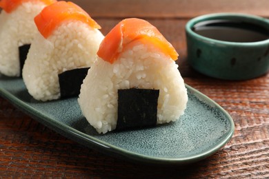 Photo of Tasty onigiri (Japanese rice balls) served on wooden table, closeup