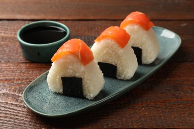 Photo of Tasty onigiri (Japanese rice balls) served on wooden table, closeup