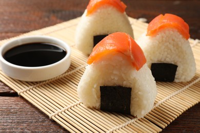 Photo of Tasty onigiri (Japanese rice balls) served on wooden table, closeup