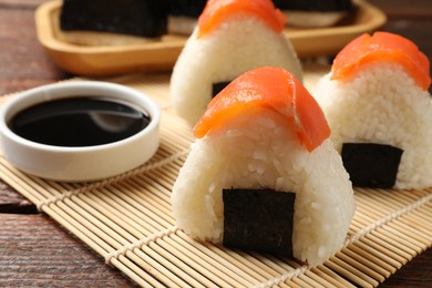 Photo of Tasty onigiri (Japanese rice balls) served on wooden table, closeup