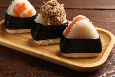 Photo of Tasty onigiri (Japanese rice balls) served on wooden table, closeup