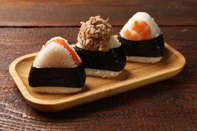 Photo of Tasty onigiri (Japanese rice balls) served on wooden table, closeup