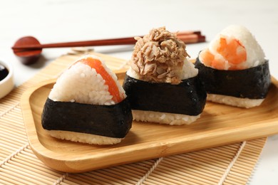 Photo of Tasty onigiri (Japanese rice balls) served on white table, closeup