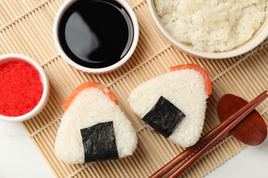 Photo of Tasty onigiri (Japanese rice balls) served on white table, flat lay
