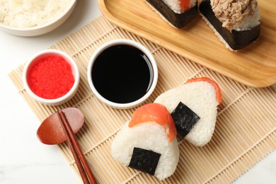 Photo of Tasty onigiri (Japanese rice balls) served on white table, flat lay
