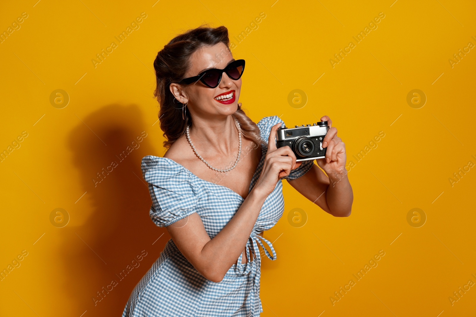 Photo of Happy pin-up woman with camera on orange background