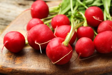 Photo of Many fresh radishes on wooden board, closeup