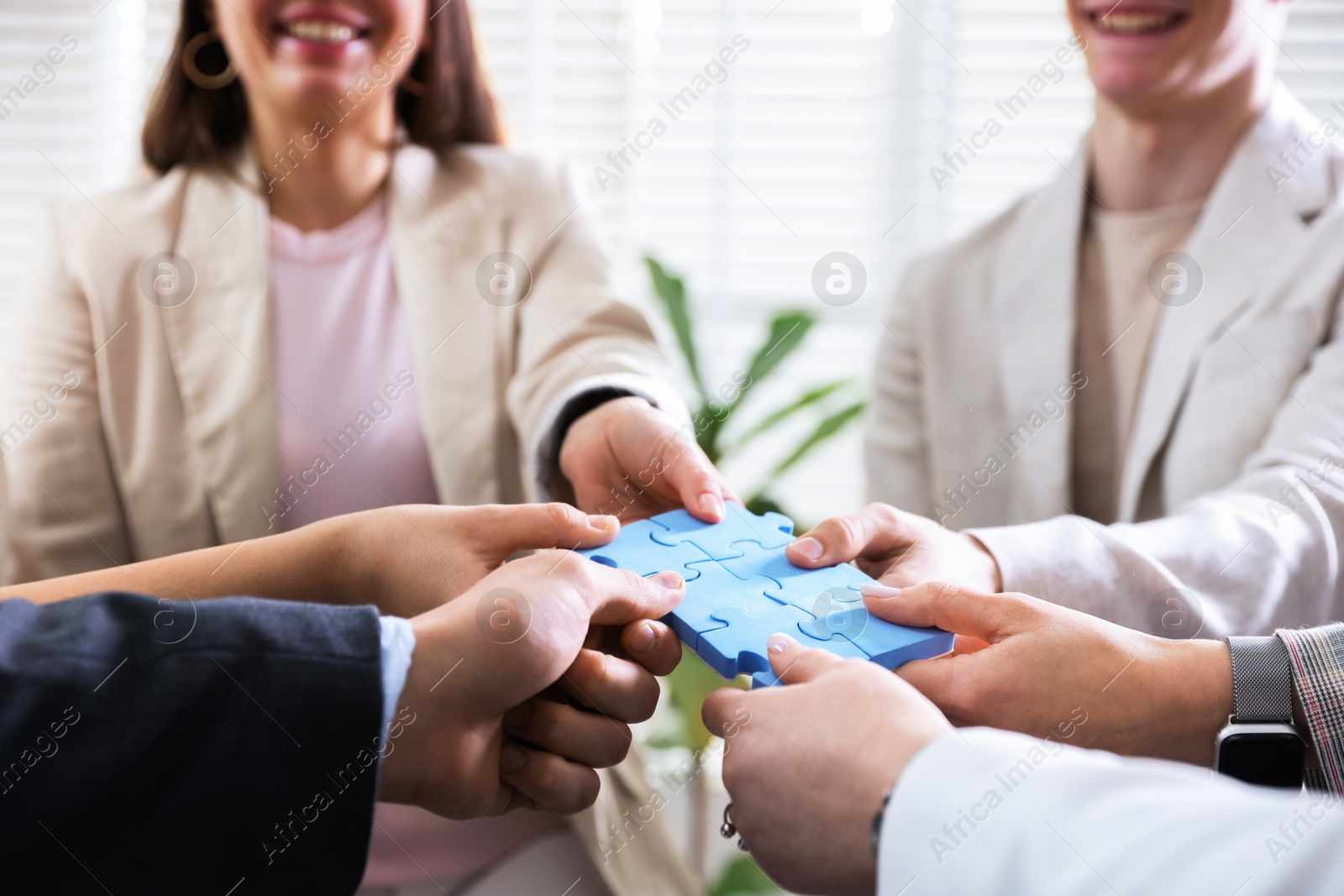 Photo of Unity concept. People putting puzzle pieces together indoors, closeup