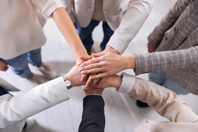 Photo of Unity concept. People holding hands together indoors, top view