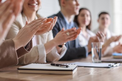 People applauding at table in office, closeup