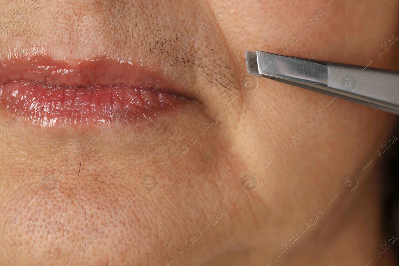 Photo of Senior woman plucking her mustache with tweezers, closeup