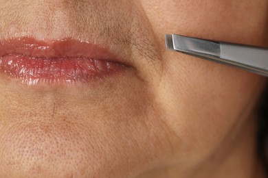 Senior woman plucking her mustache with tweezers, closeup