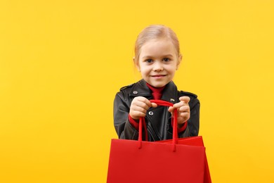 Little girl with shopping bags on orange background