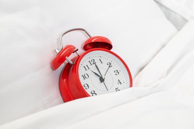 Photo of One red alarm clock in bed, closeup