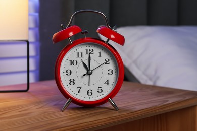 Photo of Alarm clock on wooden nightstand near bed