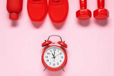 Photo of Alarm clock, sneakers, dumbbells and water bottle on pink background, flat lay