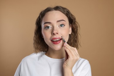 Photo of Happy woman plucking her mustache with tweezers on beige background