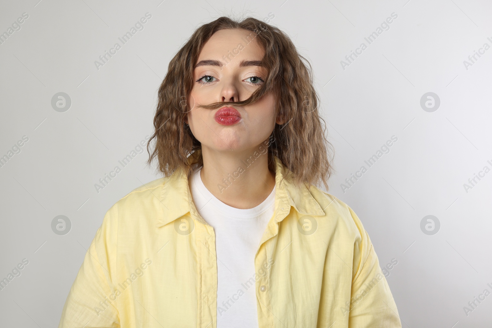 Photo of Funny woman making mustache from her hair on grey background