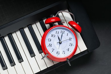 Photo of Alarm clock and electric piano on black table, above view