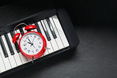 Photo of Alarm clock and electric piano on black table, above view