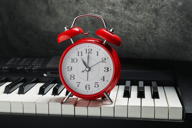 Photo of Alarm clock and electric piano on black table