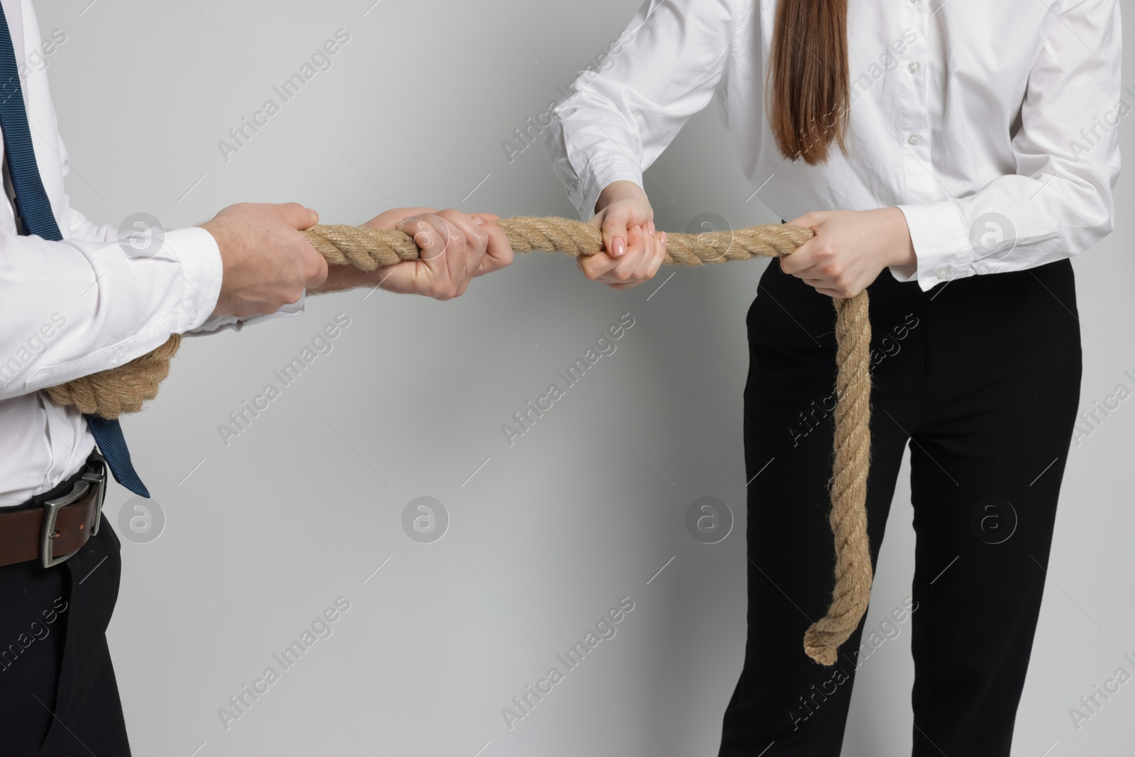 Photo of Competition concept. Businesspeople pulling rope on grey background, closeup