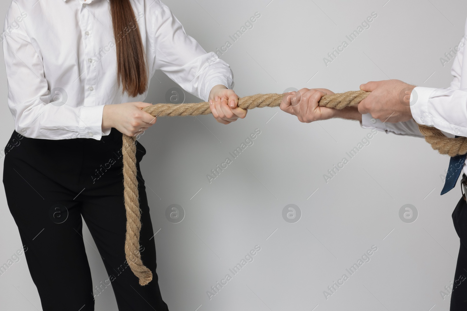 Photo of Competition concept. Businesspeople pulling rope on grey background, closeup