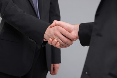 Photo of Businessmen shaking hands on grey background, closeup