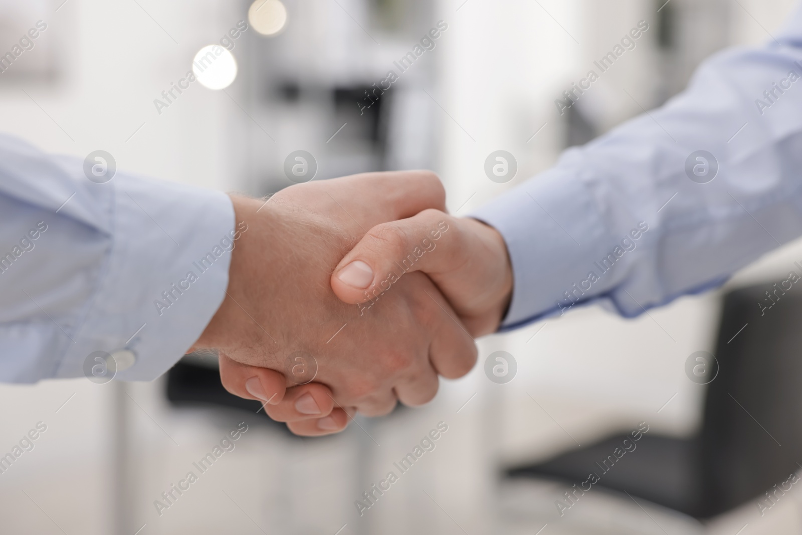 Photo of Businessmen shaking hands in agreement indoors, closeup