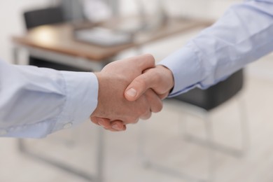 Businessmen shaking hands in agreement indoors, closeup