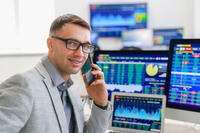 Financial trading specialist talking on phone in office