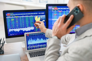 Photo of Financial trading specialist talking on phone in office, selective focus