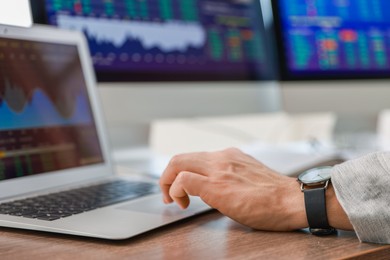 Financial trading specialist working on laptop at table in office, closeup