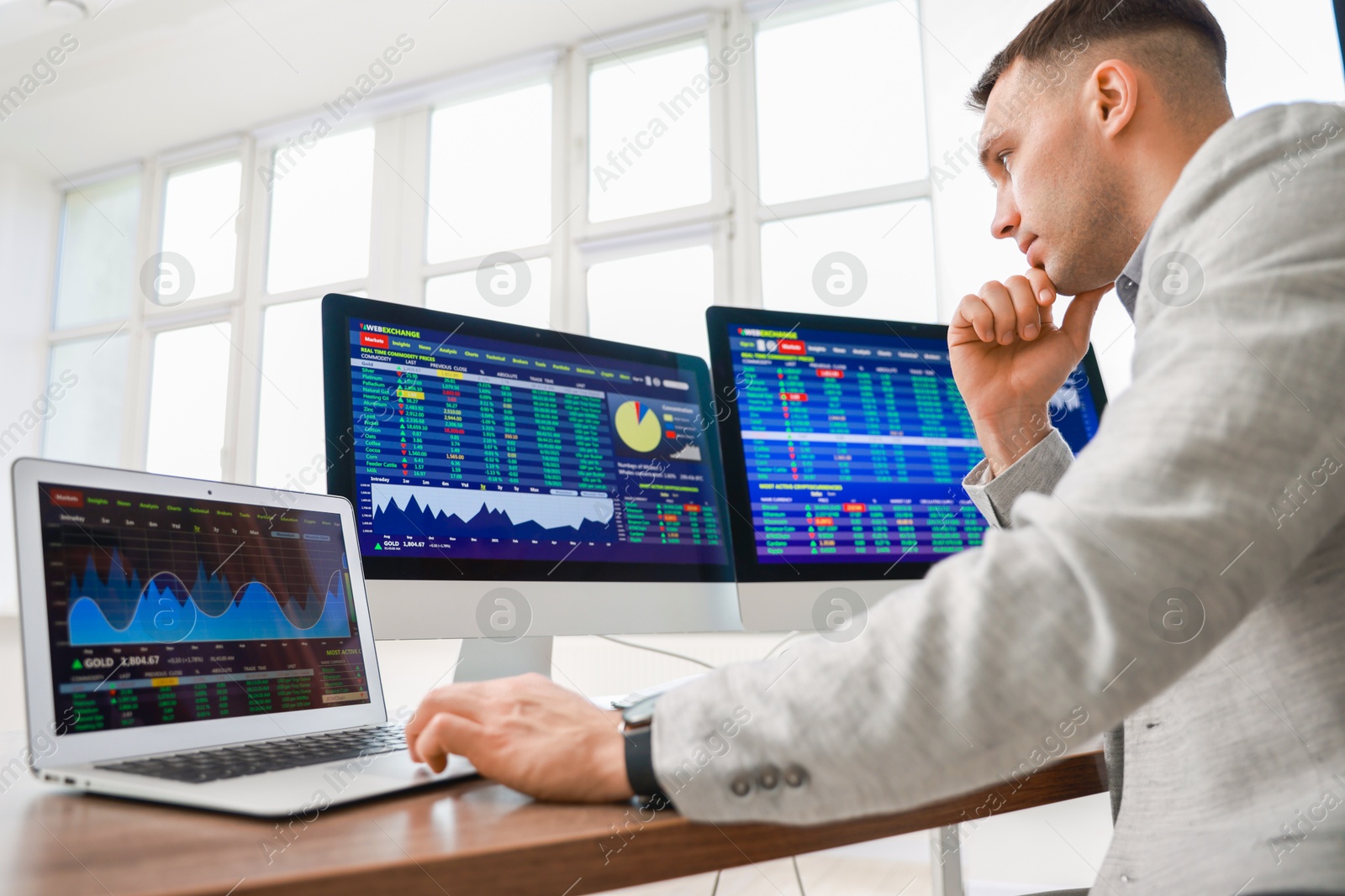 Photo of Financial trading specialist working on computer and laptop in office, low angle view