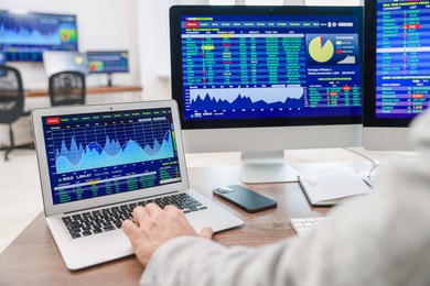 Photo of Financial trading specialist working on laptop and computer in office, closeup