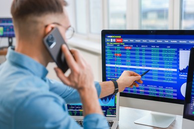 Photo of Financial trading specialist talking on phone in office, selective focus