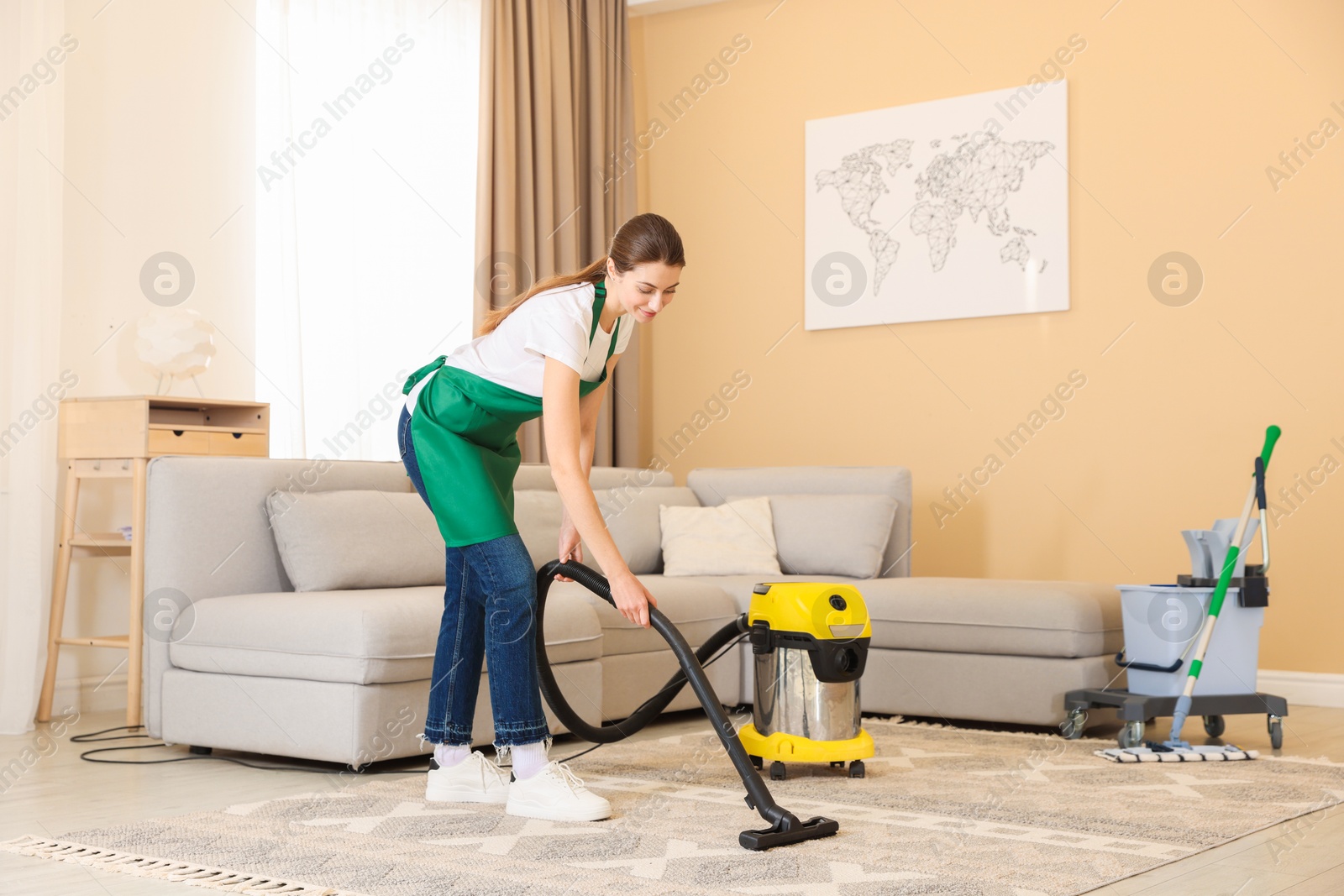 Photo of Professional cleaning service worker vacuuming rug indoors