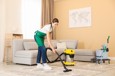 Professional cleaning service worker vacuuming rug indoors