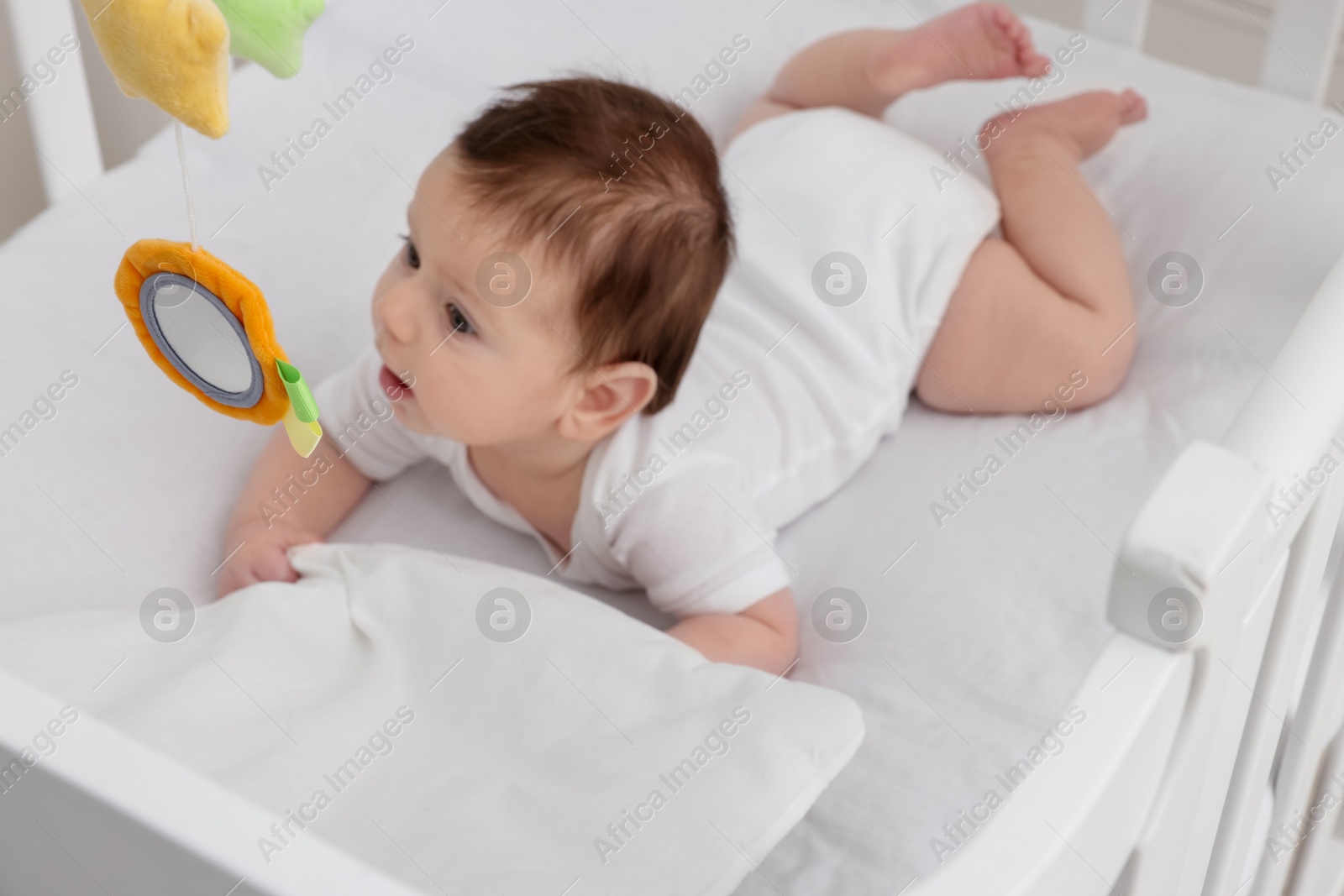 Photo of Cute little baby in crib with cot mobile at home