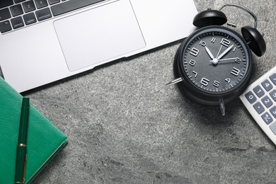 Photo of Time to pay taxes. Alarm clock, laptop, calculator and notebook on grey textured table, flat lay. Space for text