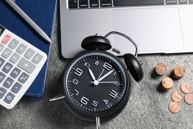 Photo of Time to pay taxes. Alarm clock, laptop, calculator, coins and notebook on grey textured table, flat lay