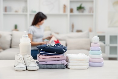 Photo of Baby's stuff on white table and mother packing bag, selective focus