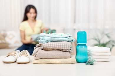 Photo of Baby's stuff on white table and mother packing bag, selective focus