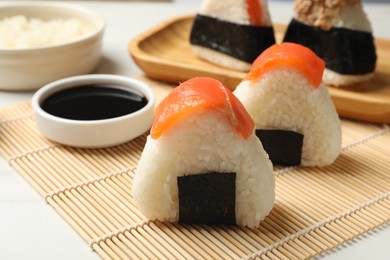 Photo of Tasty onigiri (Japanese rice balls) served on white table, closeup