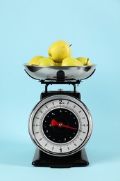 Photo of Mechanical kitchen scale with bowl of apples on light blue background