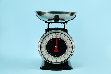 Photo of One mechanical kitchen scale on light blue background