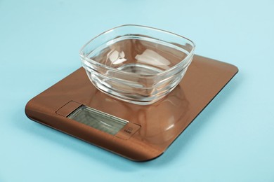 Photo of Electronic kitchen scale with empty bowl on light blue background, closeup