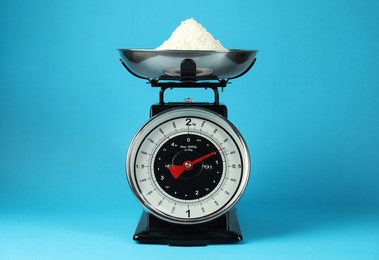 Photo of Mechanical kitchen scale with bowl of flour on blue background