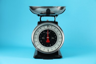 Photo of Mechanical kitchen scale with bowl on blue background